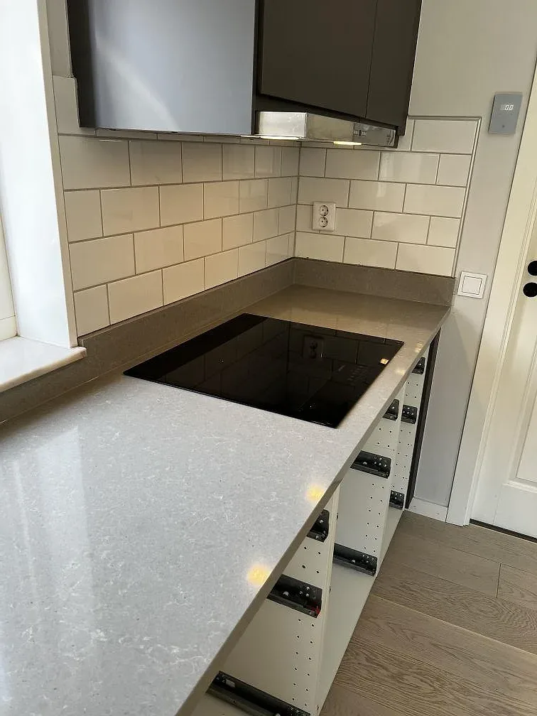 Infalld induktionshall i polerad Technistone Noble Concrete Grey kvartskomposit i ett kok i Vellinge.
