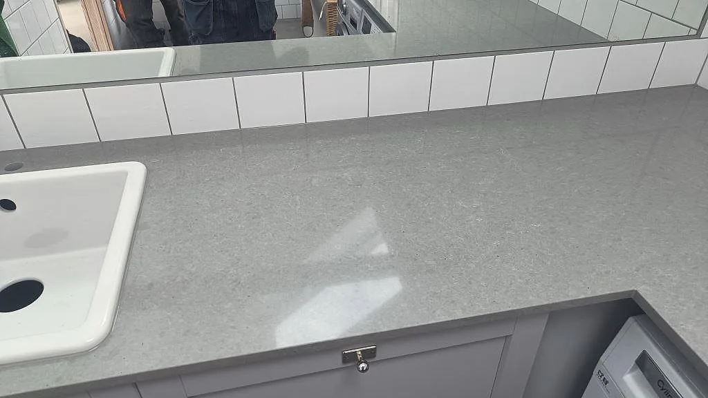Polerad Technistone Noble Concrete Grey komposityta med grå luckor och tvättmaskin i en tvättstuga i Vellinge.
