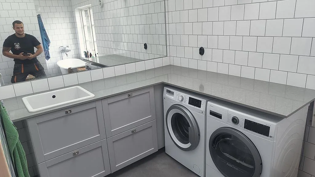 Tvättbänk i polerad Technistone Noble Concrete Grey komposit med vit övermonterad ho i en tvättstuga i Vellinge.