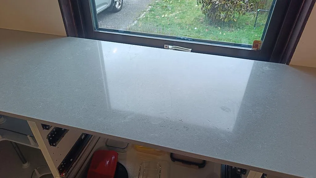 Närbild av den polerade ytan på Technistone Noble Concrete Grey kompositbänkskiva under stort fönster i Vellinge.