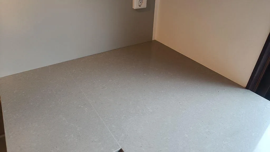 Hörndetalj av köksbänkskiva i polerad Technistone Noble Concrete Grey komposit mot vägg i Vellinge.