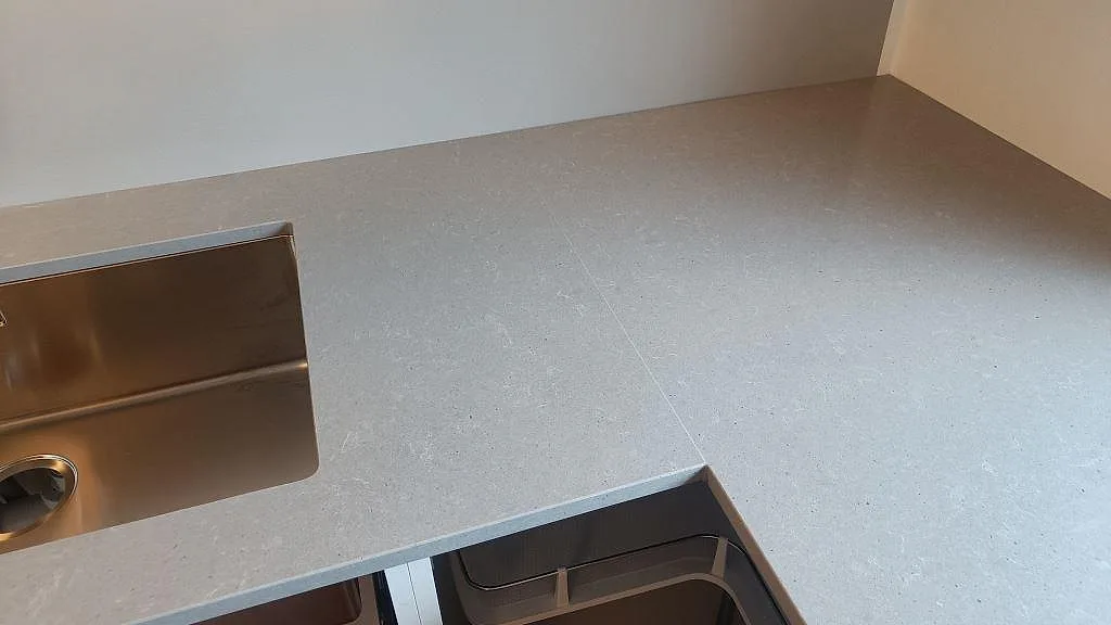 Detalj av polerad Technistone Noble Concrete Grey komposit med underlimmad rostfri diskho och hörnyta i kök i Vellinge.