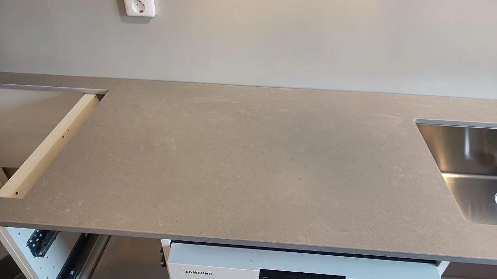 Polerad kompositbänkskiva i Technistone Noble Concrete Grey med diskho och hällurtag under montering i Vellinge.