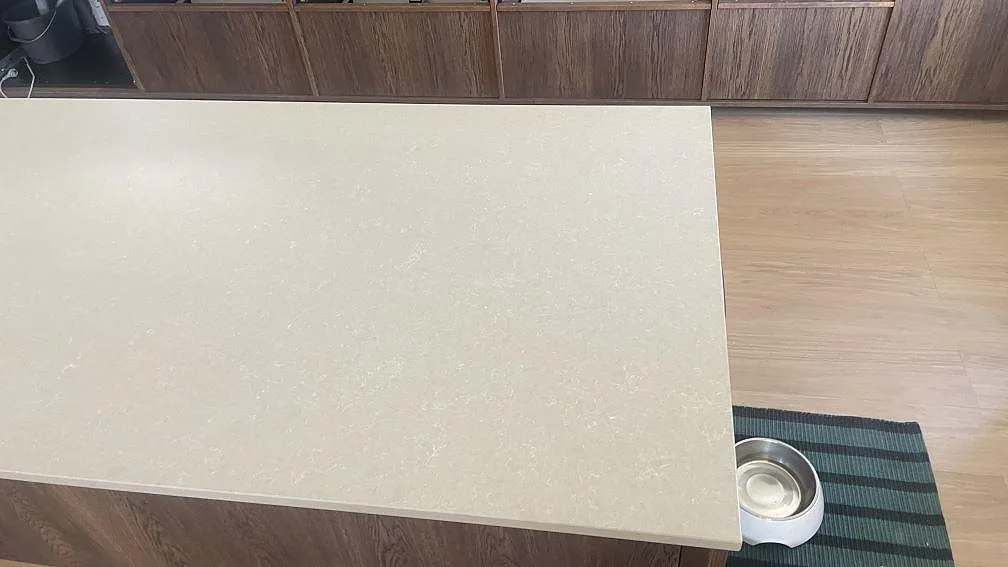 Köksö med polerad skiva i Technistone Noble Ivory White, ljus kvartskomposit med diskret struktur i ett kök i Åhus.