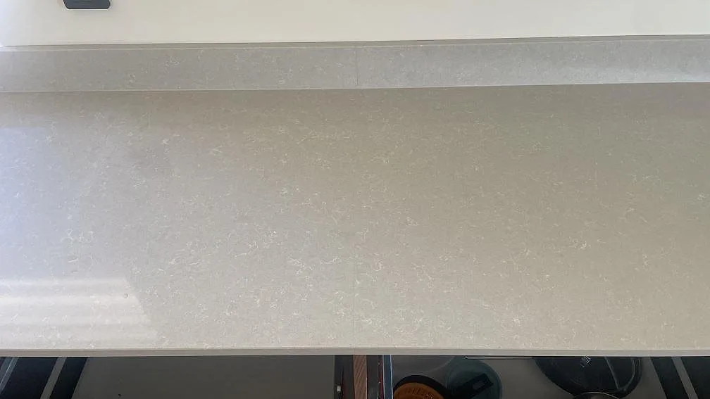 Detalj av den polerade ytan i Technistone Noble Ivory White, ljus kvartskomposit på en rak köksbänk med stänkkant i Åhus.