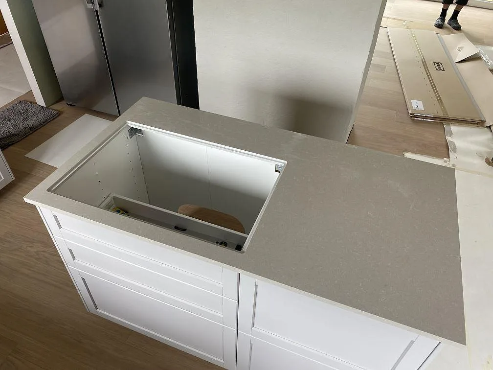 Bänkskiva i Technistone Noble Ivory White, polerad kvartskomposit, med synlig urskärning i en badrumsinredning under färdigställande i Ängelholm.