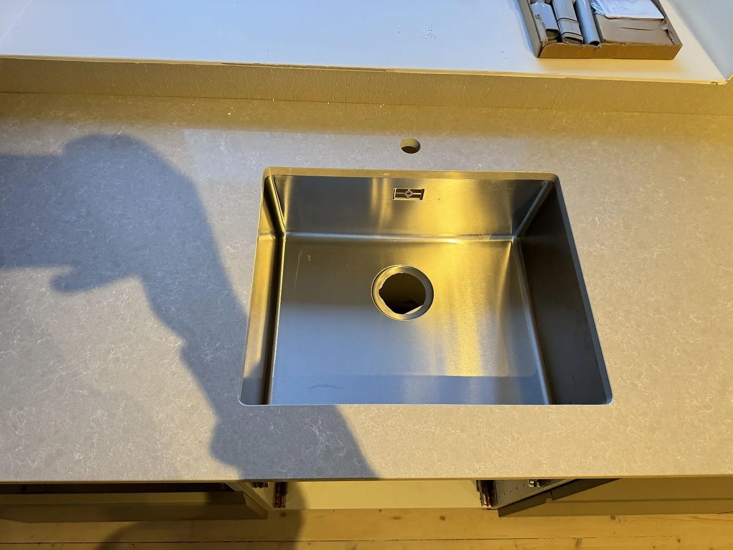 Närbild på underlimmad rostfri diskho i polerad Technistone Noble Ivory White med blandarhål bakom hon i Ängelholm.
