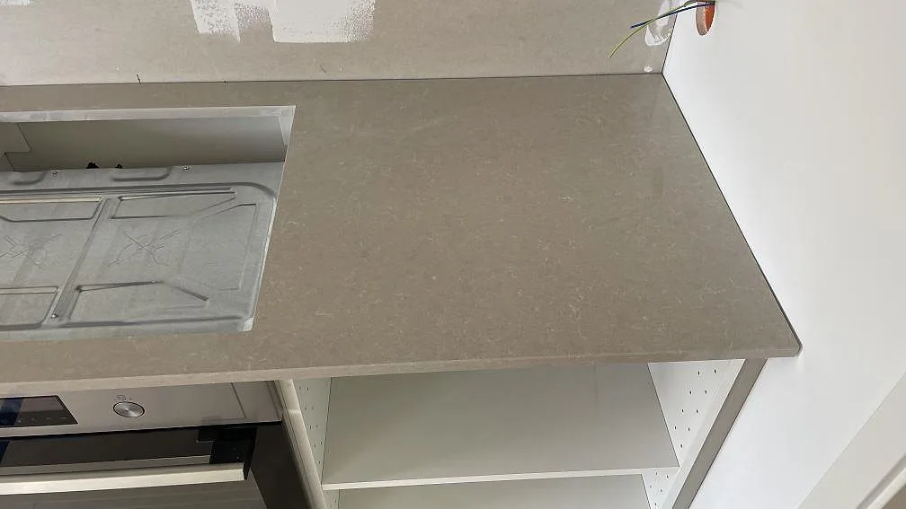 Högersida av köksbänkskiva i Technistone Noble Ivory White, polerad kvartskomposit, vid hälluttag och öppna stommar i Dalsjöfors.