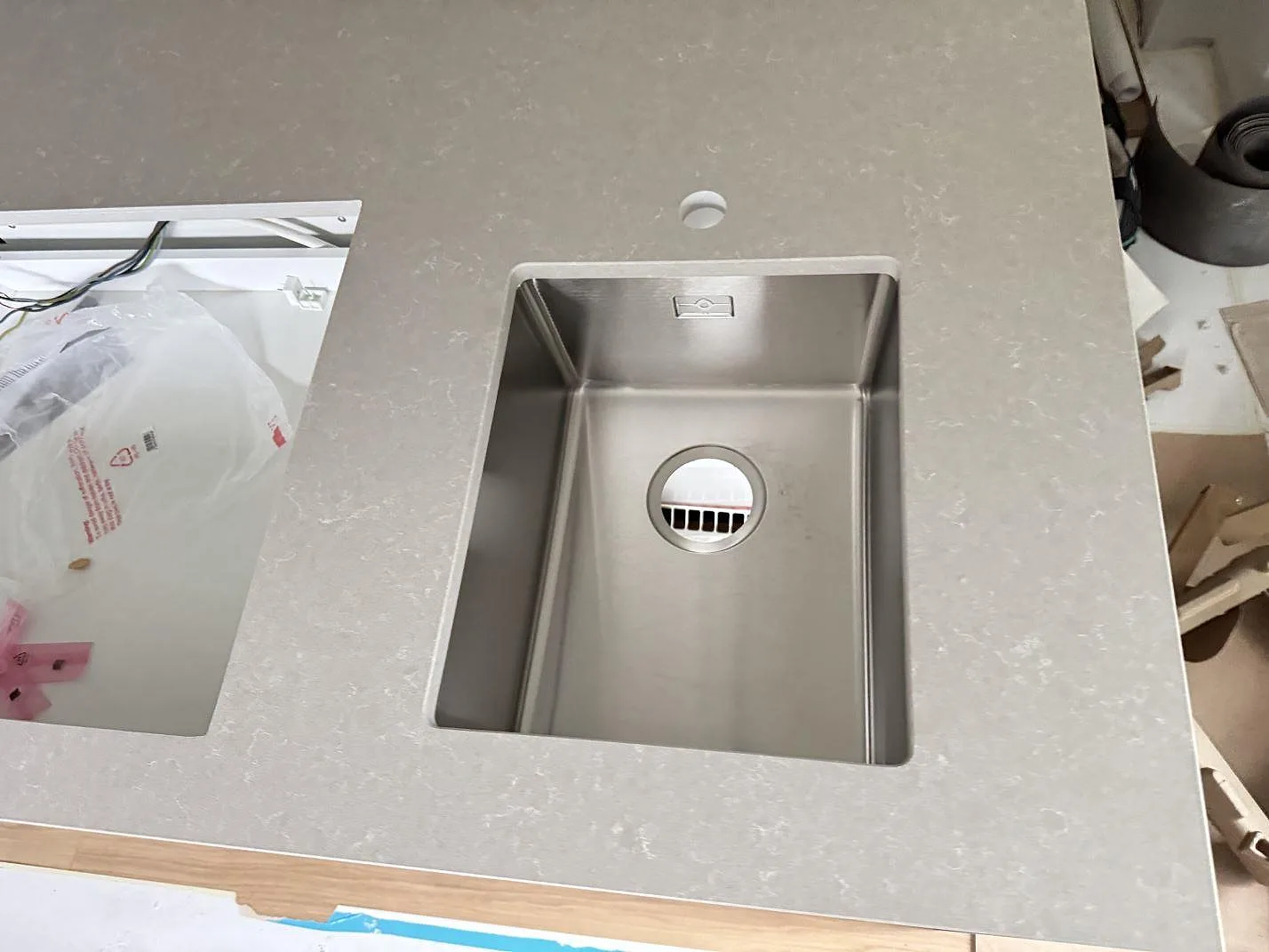 Detalj av köksö i polerad Technistone Noble Ivory White komposit med rostfri diskho och rektangulärt urtag i Eksjö.