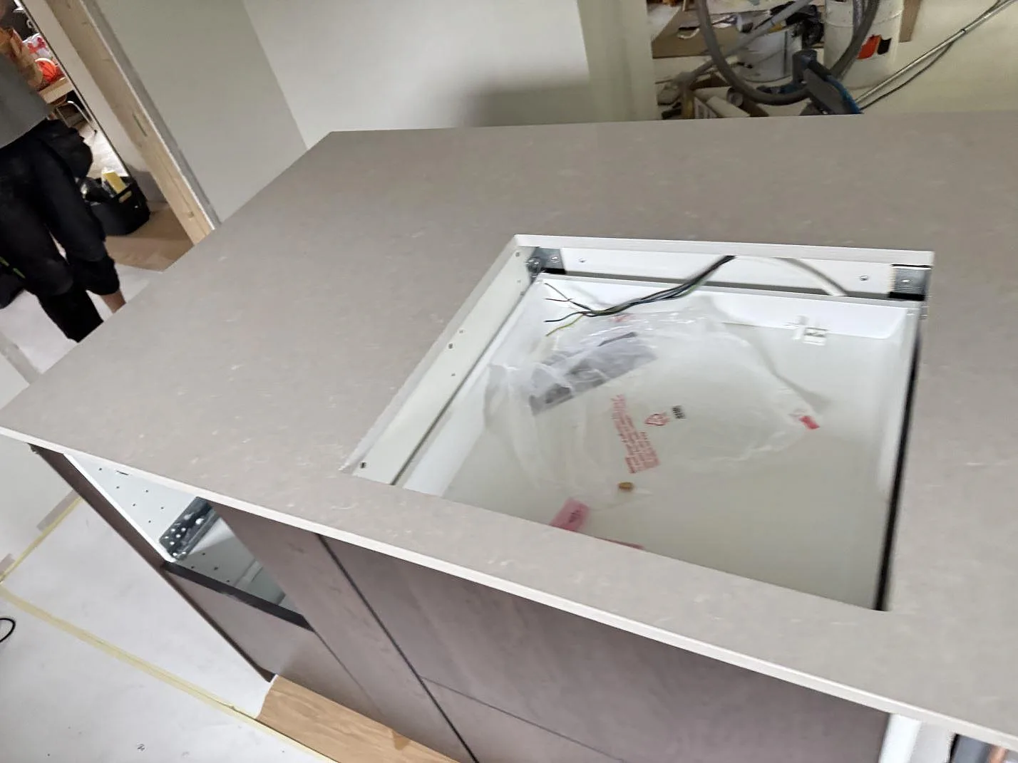 Detalj av polerad Technistone Noble Ivory White komposit runt ett rektangulärt urtag på köksön under montering i Eksjö.