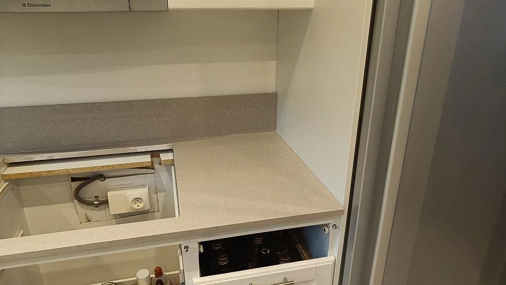 Sidovy av hällöppning och ljus polerad Technistone Noble Ivory White köksbänk med stänkkant i ett kök i Eslöv.