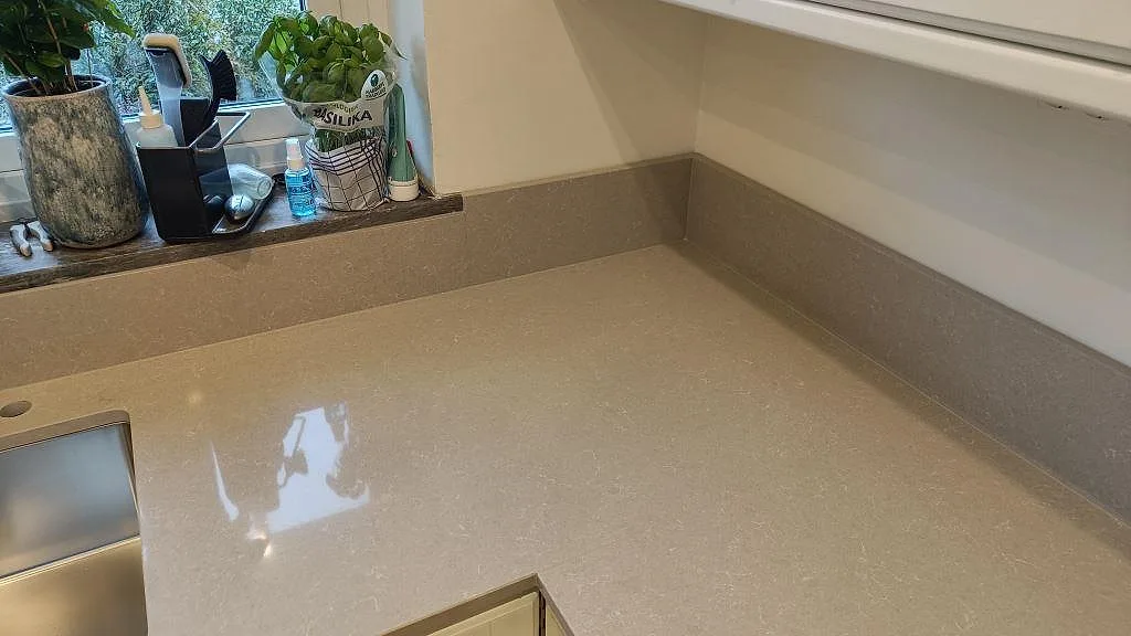 Närbild av polerad Technistone Noble Ivory White som köksbänkskiva med diskho, fönsterhörn och uppvikt stänkkant i Eslöv.