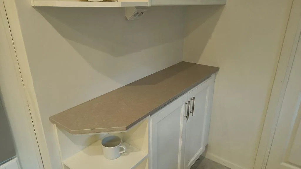 Separat bänkdel i polerad Technistone Noble Ivory White på vit köksförvaring med fasad framkant i Eslöv.