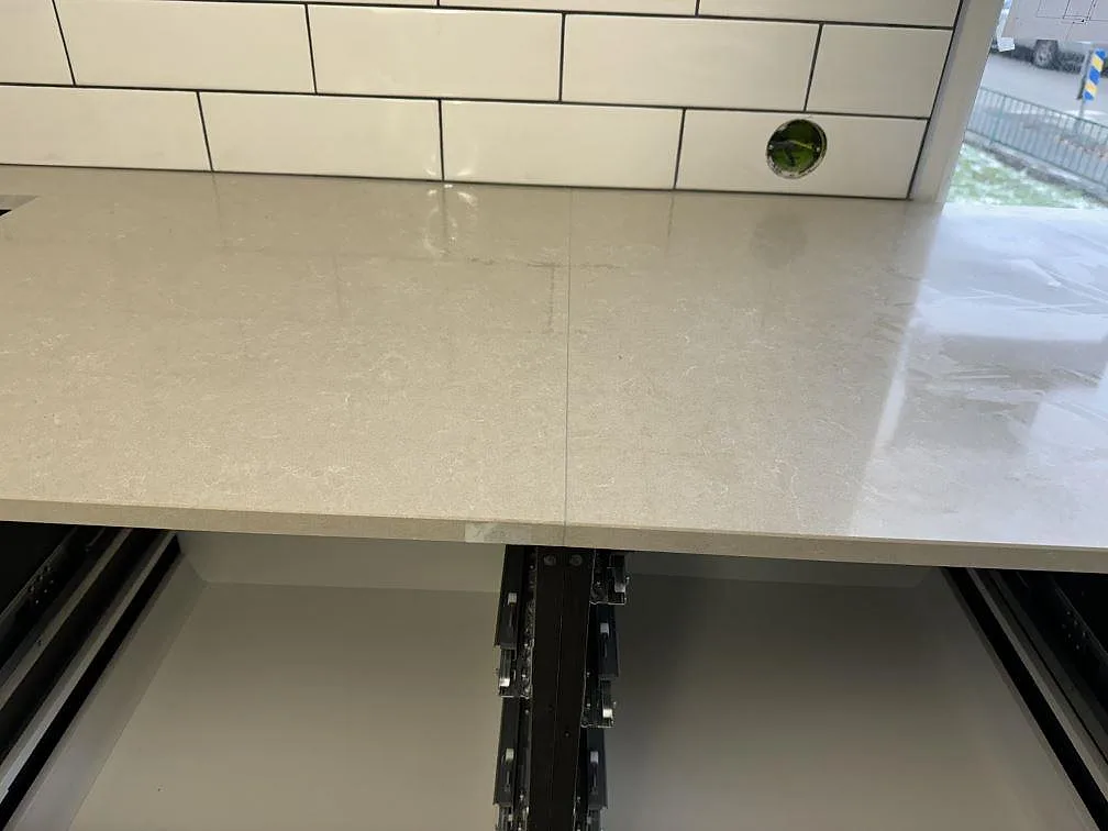 Blank ljus kvartskomposityta i Technistone Noble Ivory White över öppna köksstommar under montering i Falköping.
