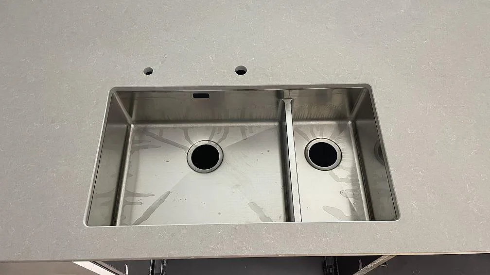 Detaljbild av köksö med polerad Technistone Noble Ivory White och rostfri diskho i ett kök i Frillesås.