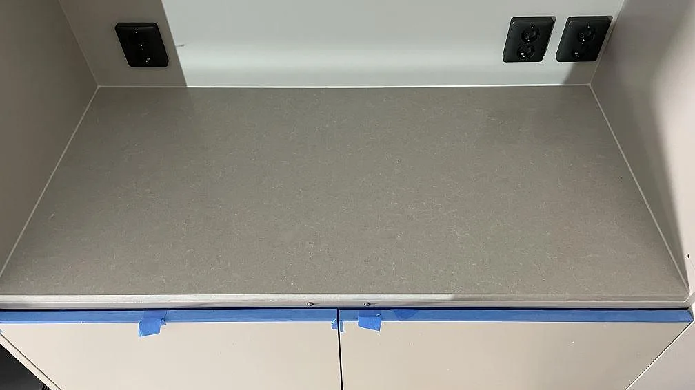 Polerad bänkskiva i Technistone Noble Ivory White med låg stänkkant och svarta eluttag i Frillesås.