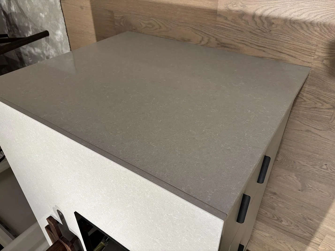 Detalj av köksöns polerade Technistone Noble Ivory White med ljus yta och träinredning i Gnosjö.