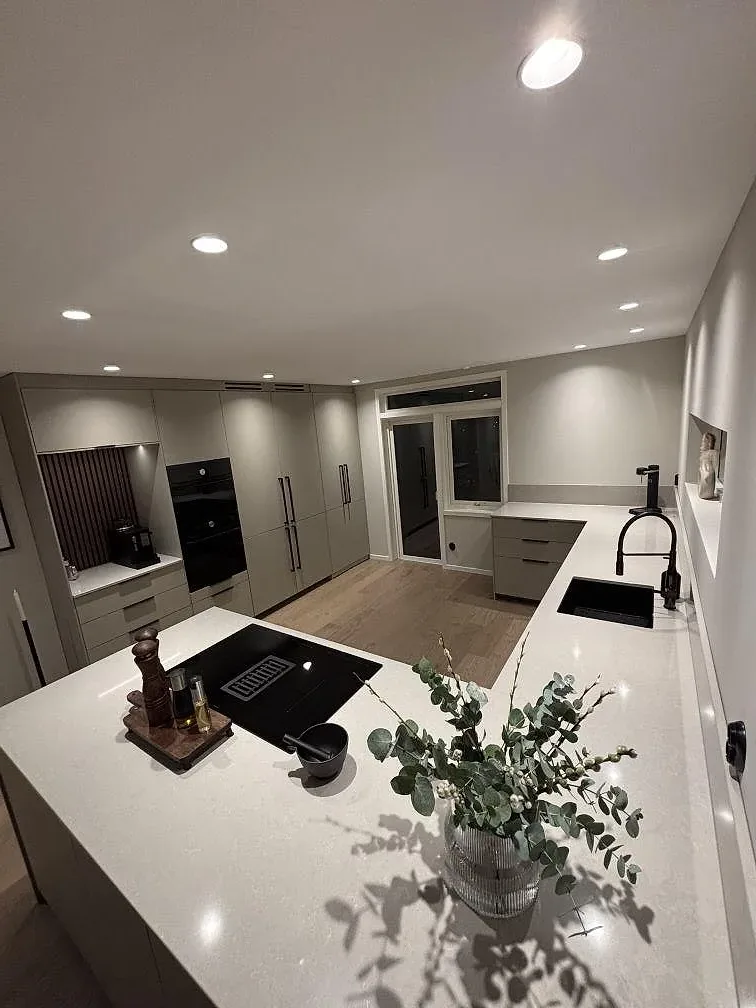 Översikt av polerad Technistone Noble Ivory White som köksbänkskiva med köksö, svart diskho och häll i Gnosjö.