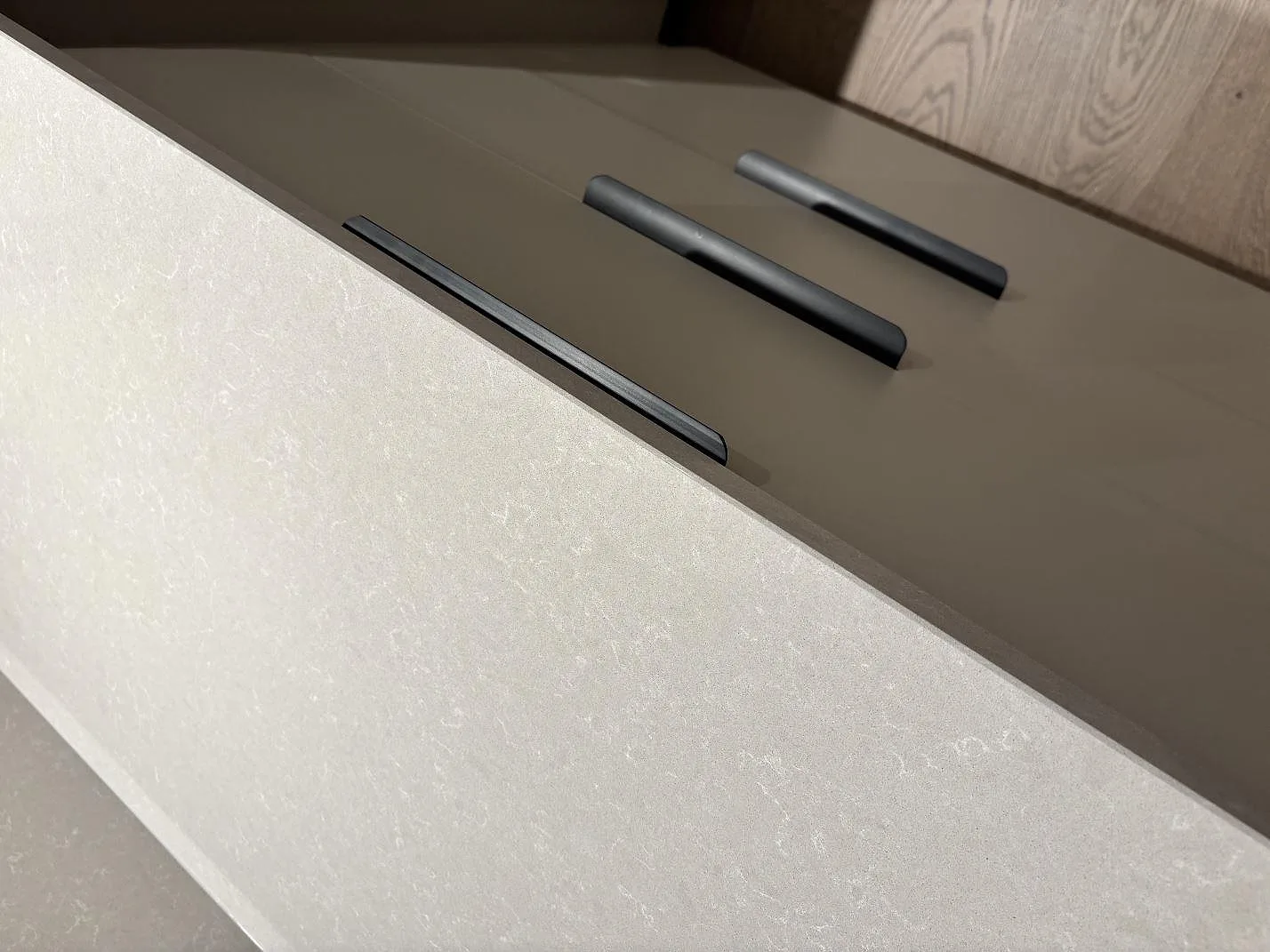 Närbild av kanten på en polerad Technistone Noble Ivory White bänkskiva i komposit vid kökslådor i Gnosjö.