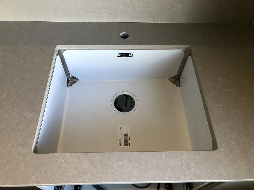 Ovanifrån på underlimmad diskho infälld i en köksbänkskiva i matt Technistone Noble Ivory White, Göteborg.