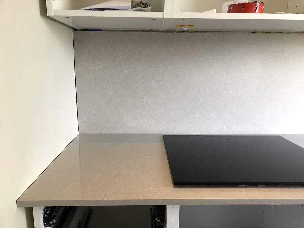 Köksbänkskiva i Technistone Noble Ivory White med uppvikt stänkskydd och induktionshäll under montering i ett kök i Göteborg.