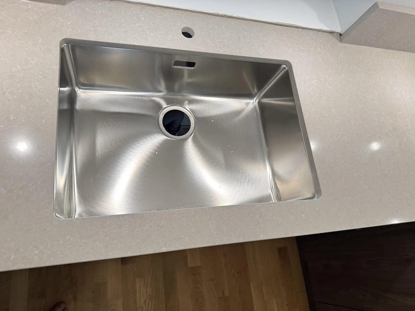 Rostfri diskho i en köksbänkskiva av polerad kvartskomposit, Technistone Noble Ivory White, i Göteborg.