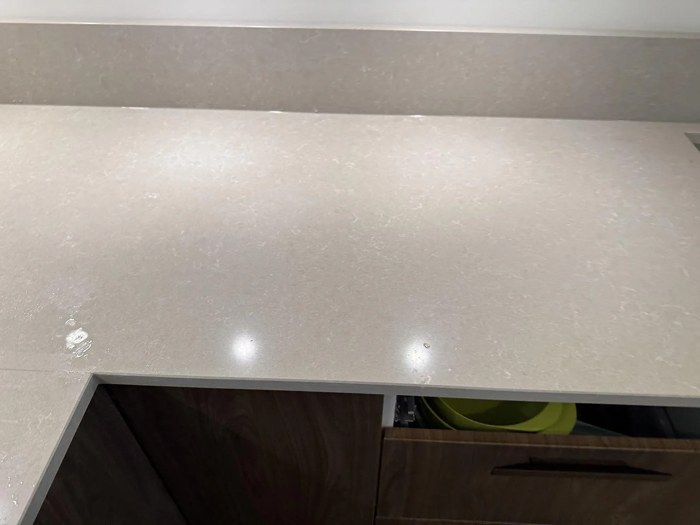 Rak bänklängd i polerad kvartskomposit, Technistone Noble Ivory White, med stänkkant över mörka träfronter i Göteborg.