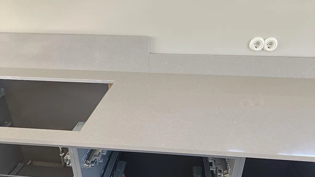 Närbild av polerad Technistone Noble Ivory White som köksbänkskiva med hälluttag och stänkskydd i Göteborg.