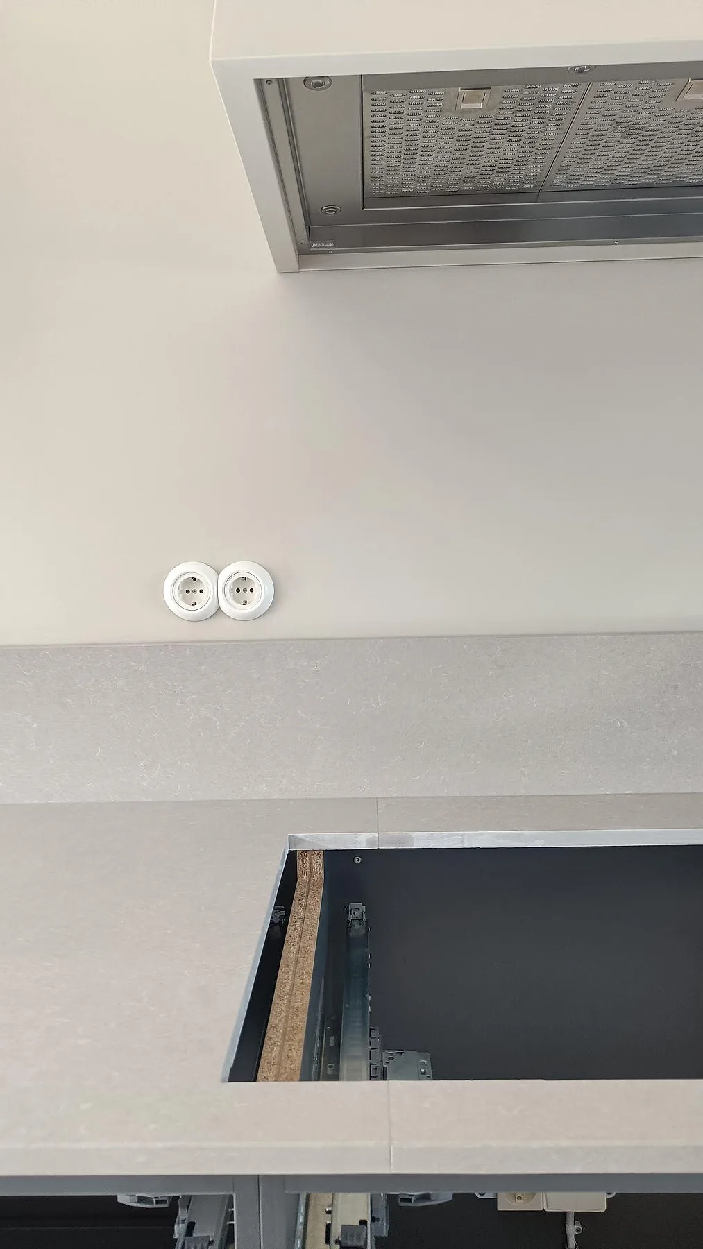 Vertikal bild av hälluttag och stänkskydd i en polerad bänkskiva av Technistone Noble Ivory White i Göteborg.