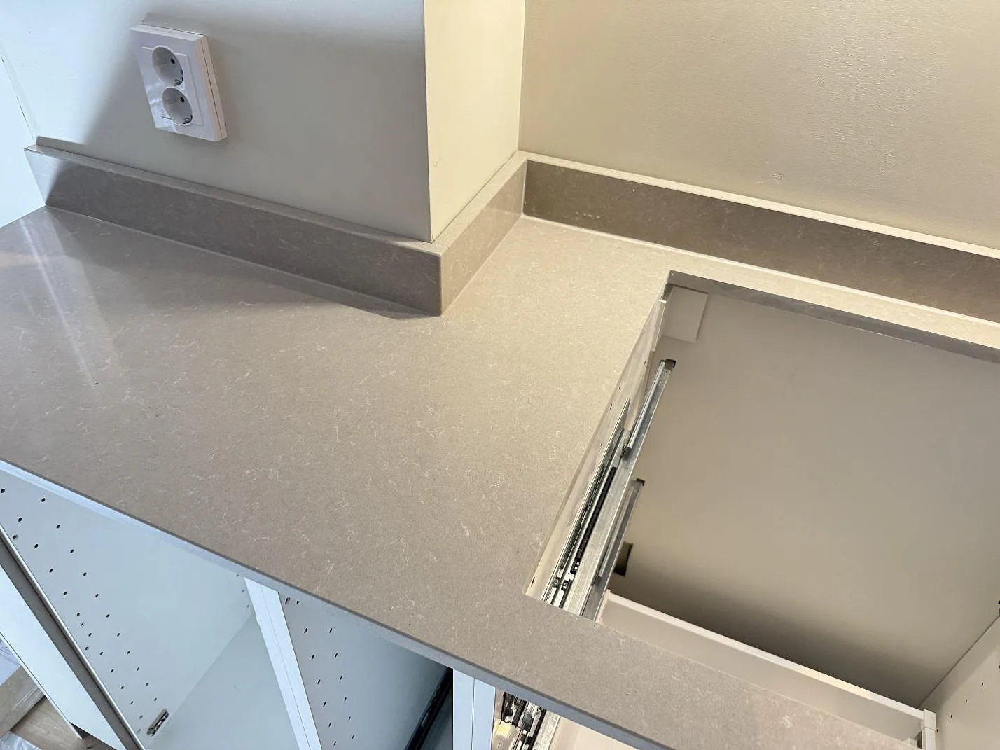 Närbild av polerad Technistone Noble Ivory White som kompositbänkskiva, med låg stänkkant och rektangulärt urtag i köket i Göteborg.