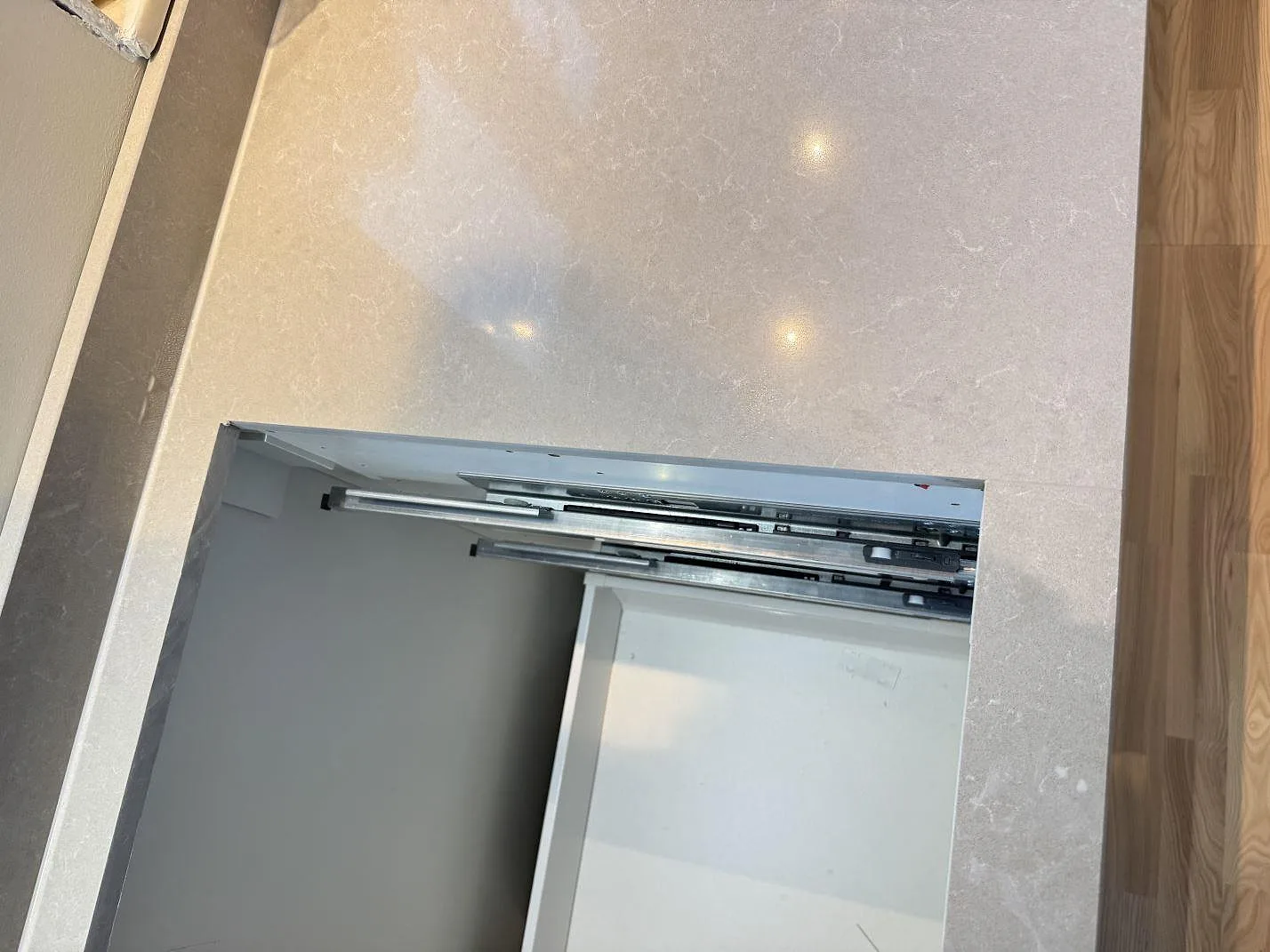 Detalj av ljus polerad Technistone Noble Ivory White-komposit runt ett rektangulärt urtag i köket i Göteborg.