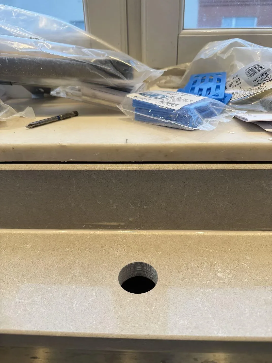 Detalj av polerad Technistone Noble Ivory White i komposit, med runt blandarhål, stänkkant och fönsterläge i köket i Göteborg.