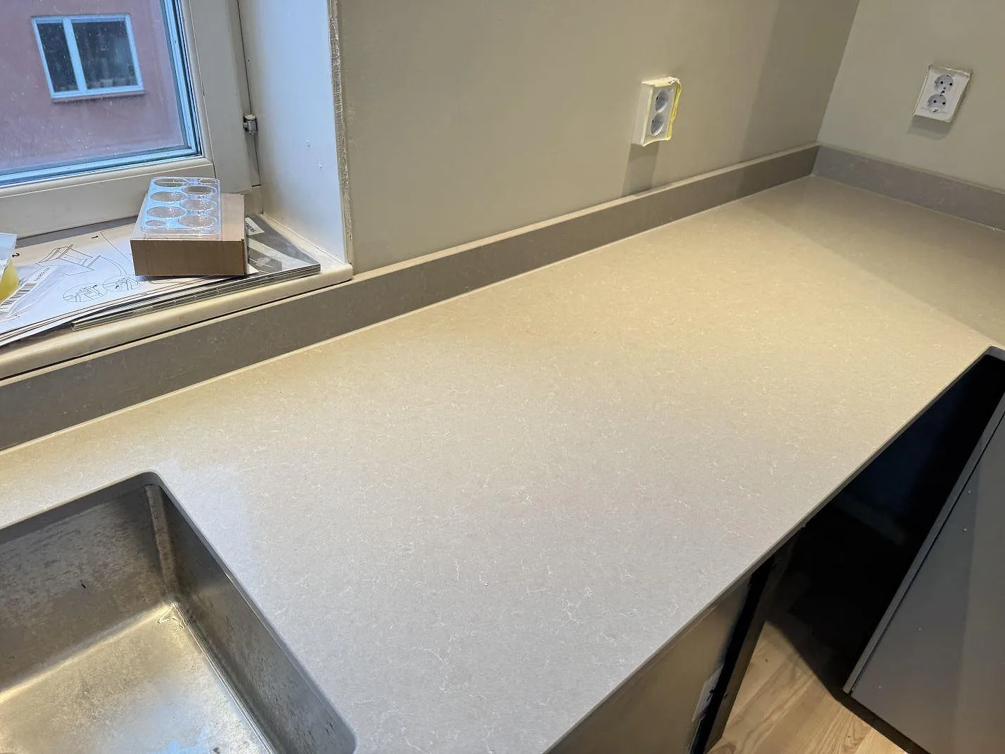 Polerad kvartskomposit i Technistone Noble Ivory White vid diskhon, med ljus köksbänk och stänkkant i Göteborg.