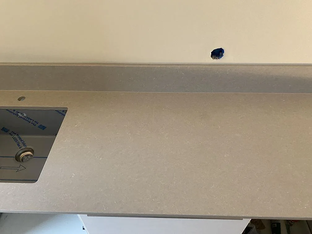 Närbild på polerad Technistone Noble Ivory White med diskho i kanten, blandarhål och uppvikt stänkkant i Helsingborg.