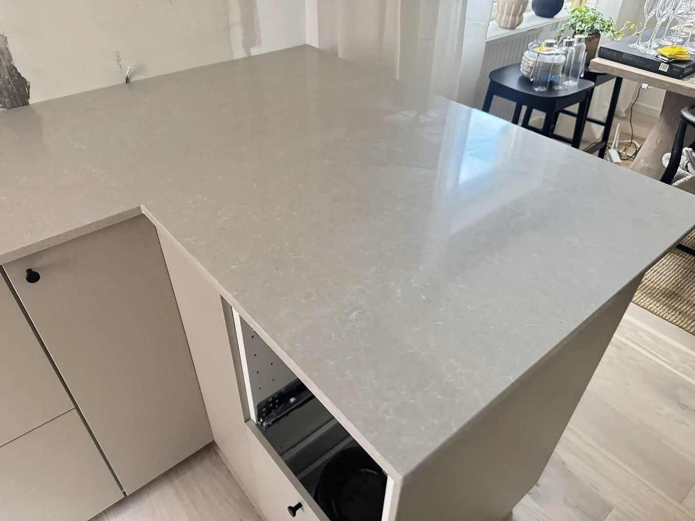 Närbild av den polerade halvön i Technistone Noble Ivory White, ljus kvartskomposit med reflektioner från fönster i ett kök i Helsingborg.