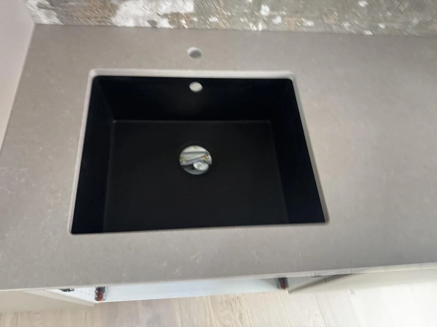 Närbild av svart diskho i polerad Technistone Noble Ivory White, ljus kvartskomposit med fin teckning, i ett kök i Helsingborg.