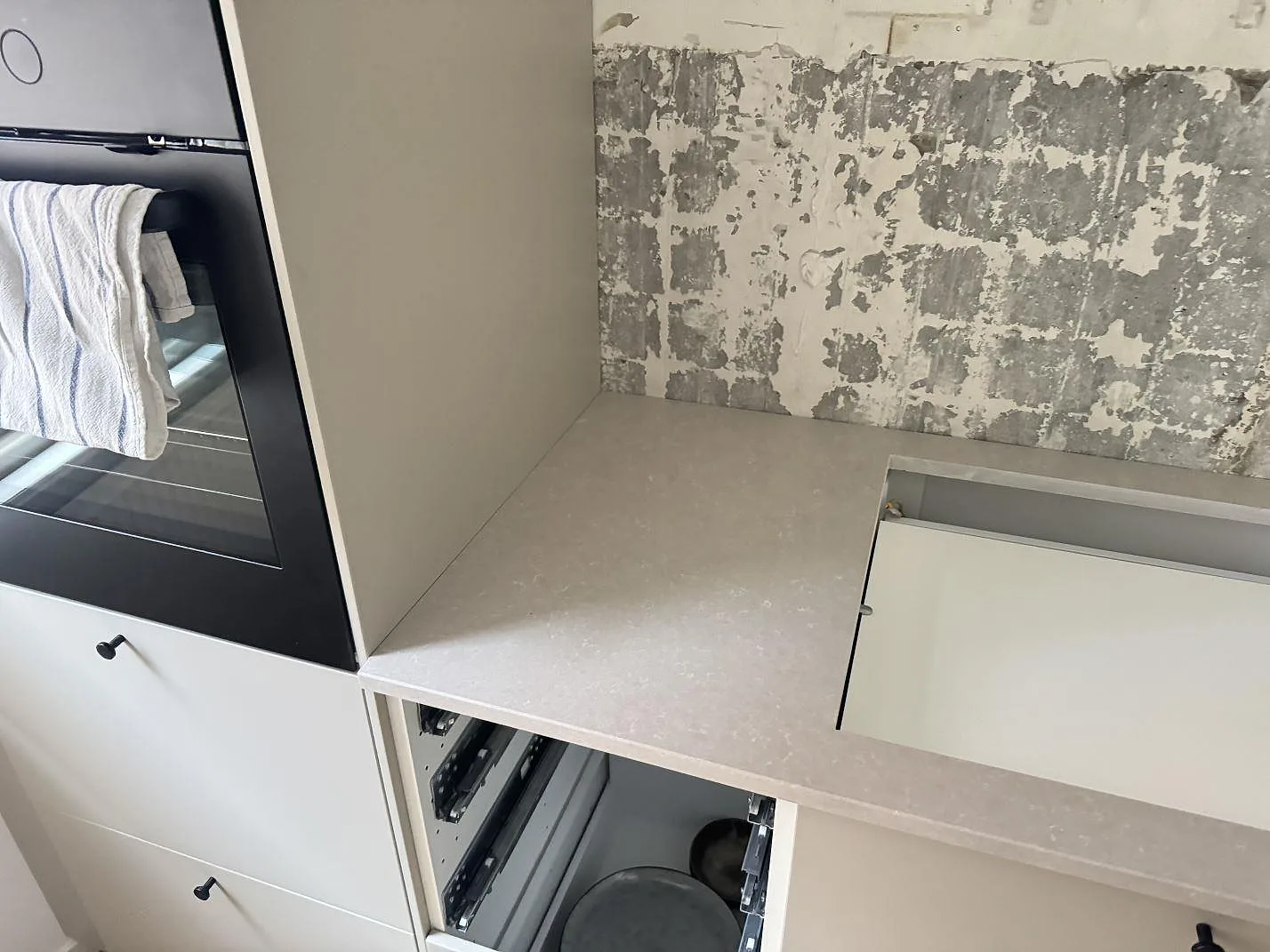 Väggbänk i Technistone Noble Ivory White med öppning för häll, polerad kvartskomposit, monterad mot köksstommar i Helsingborg.