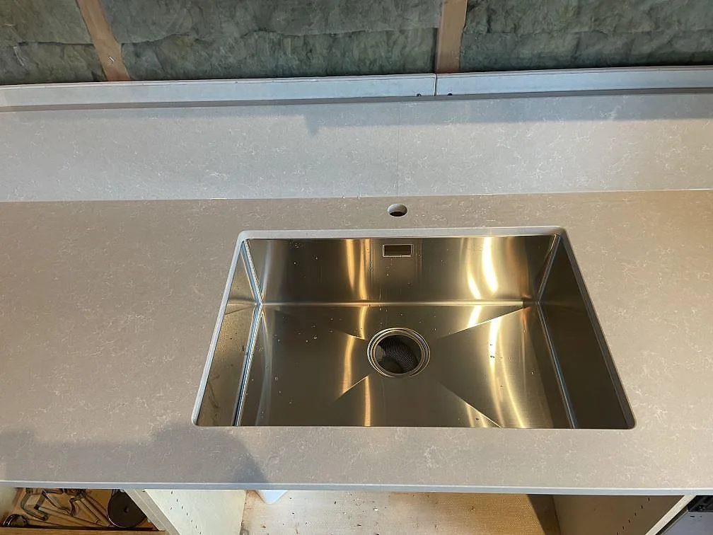 Rostfri diskho och blandarhål i polerad Technistone Noble Ivory White köksbänkskiva av kvartskomposit i Hisings kärra.