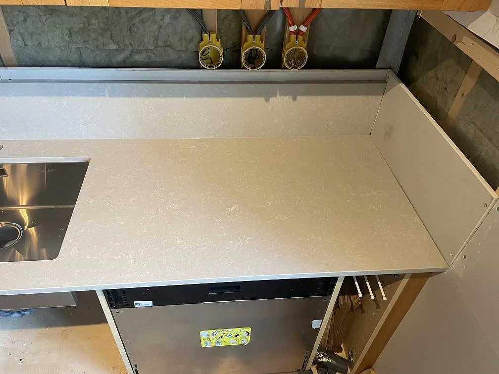 Höger bänkdel i polerad Technistone Noble Ivory White komposit med rostfri diskho, stänkkant och öppna stommar i Hisings kärra.