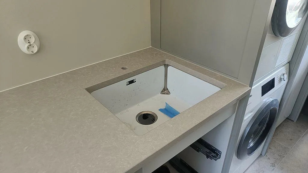 Underlimmad diskho i en bänkskiva av Technistone Noble Ivory White i en tvättdel intill köket i Höllviken.