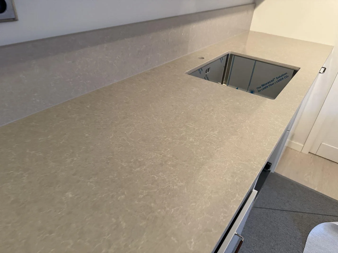 Köksbänkskiva i polerad Technistone Noble Ivory White med uppvikt stänkkant och underlimmad diskho i Höllviken.