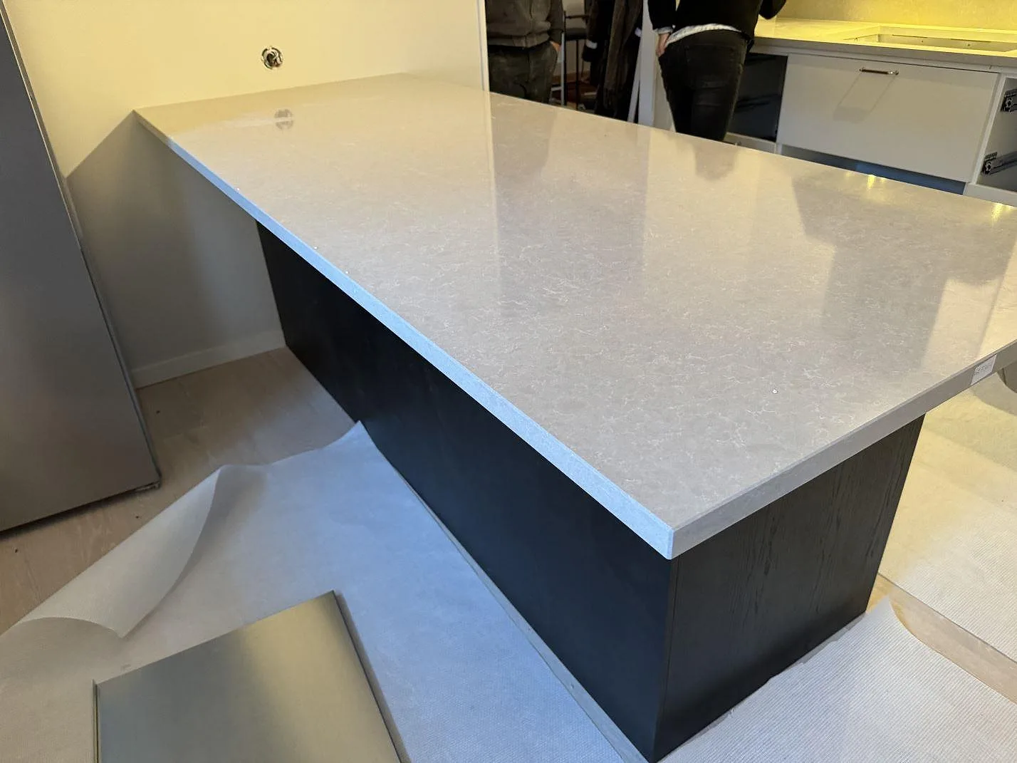 Polerad köksö i Technistone Noble Ivory White med ljus ådring och mörk stomme under montering i Höllviken.