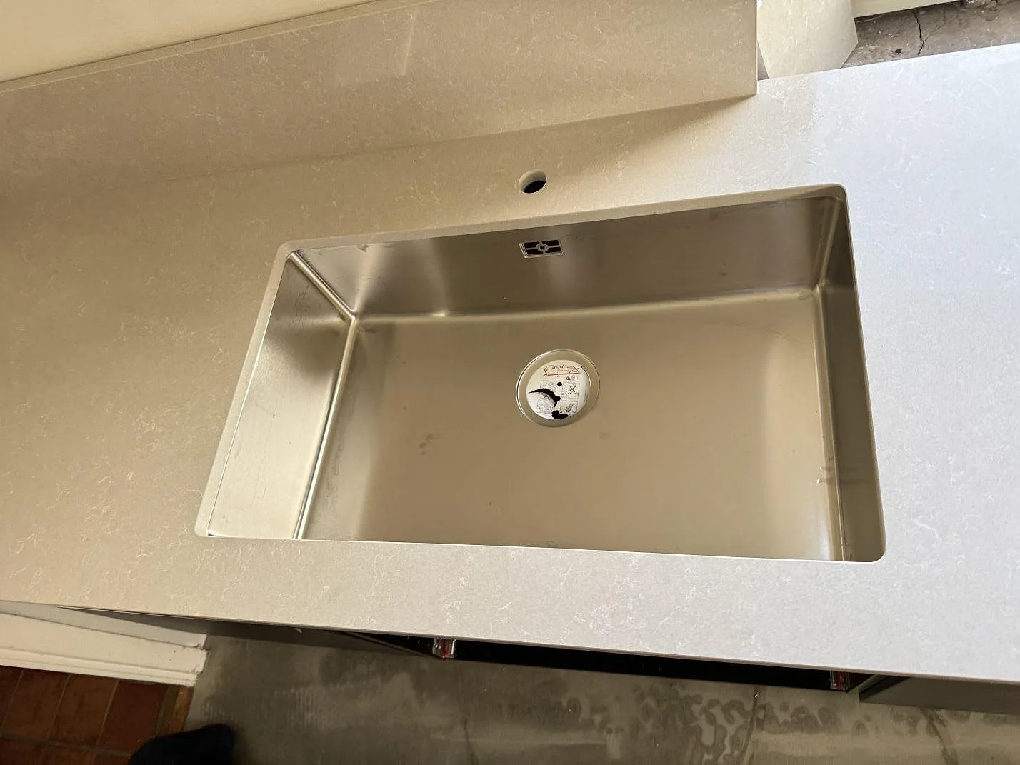 Närbild av polerad Technistone Noble Ivory White i kvartskomposit med rostfri diskho monterad under stenen i köket i Hovås.