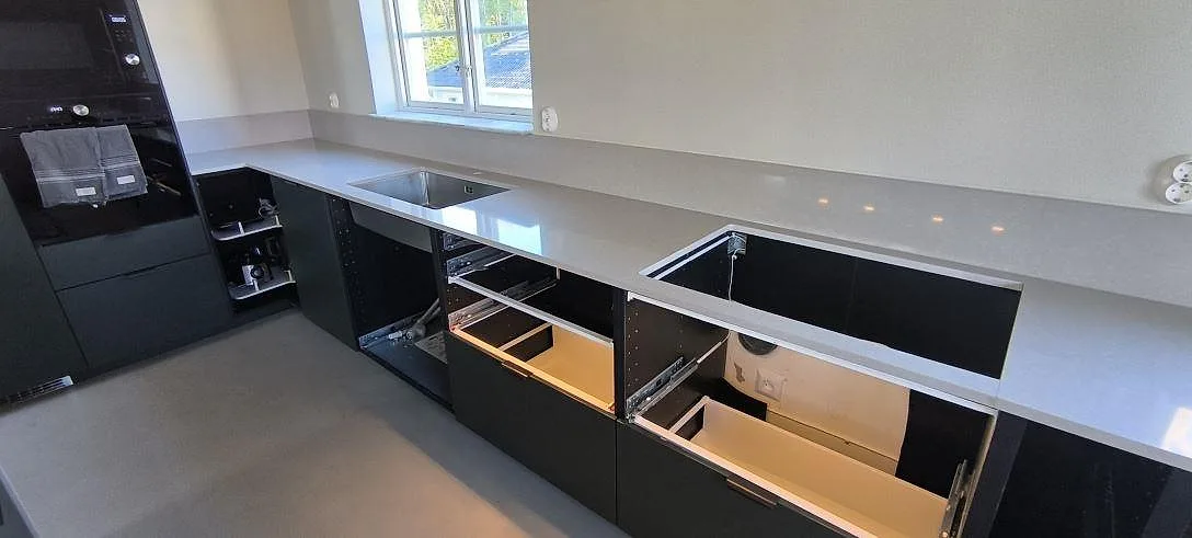 Lång bänkskiva i Technistone Noble Ivory White, polerad kvartskomposit, med rostfri diskho och förberedd hällöppning i Huddinge.