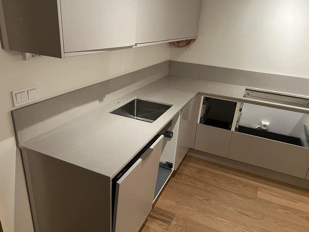 Polerad köksbänkskiva i Technistone Noble Ivory White med uppvikt stänkkant och synlig arbetsyta i köket i Järfälla.