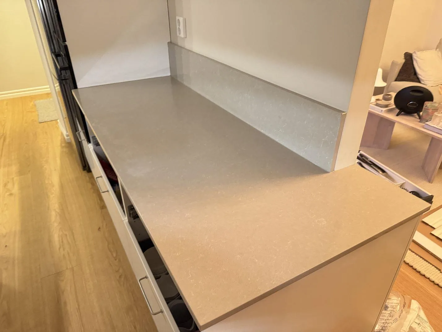 Lång köksbänkskiva i polerad Technistone Noble Ivory White komposit med låg stänkkant och ljus vägg i ett kök i Jönköping.