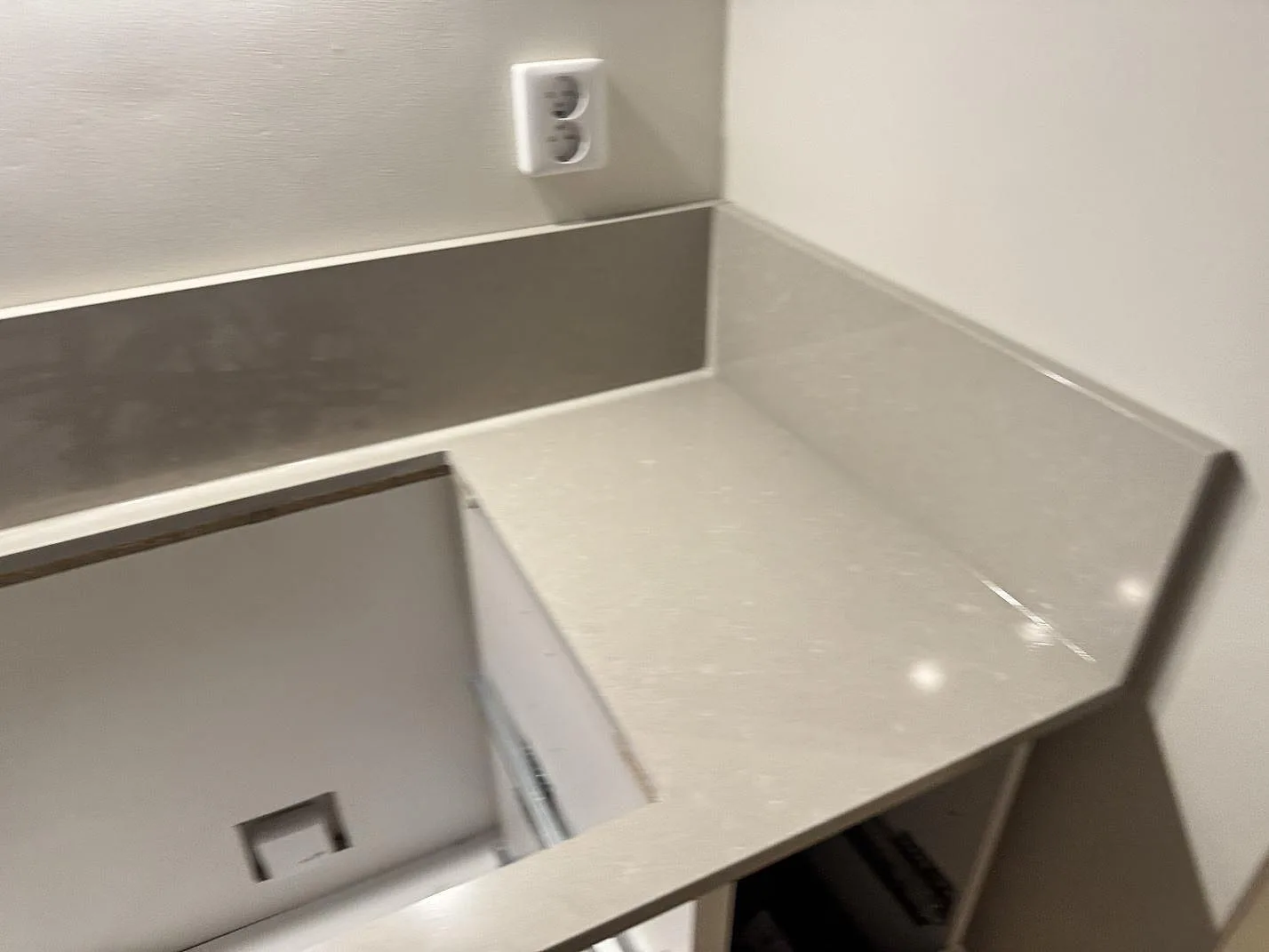 Hörndetalj av polerad Technistone Noble Ivory White bänkskiva och stänkkant på öppna köksstommar under montering i Jönköping.