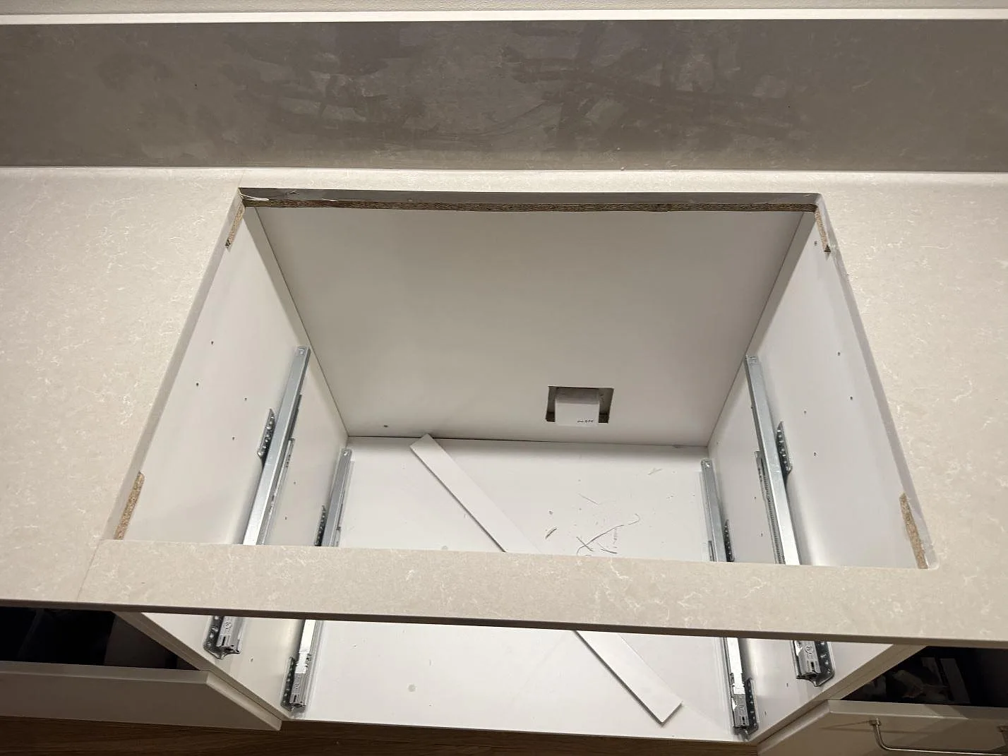 Detalj av hällöppning i polerad Technistone Noble Ivory White komposit på en köksbänkskiva med uppvikt stänkkant i Jönköping.