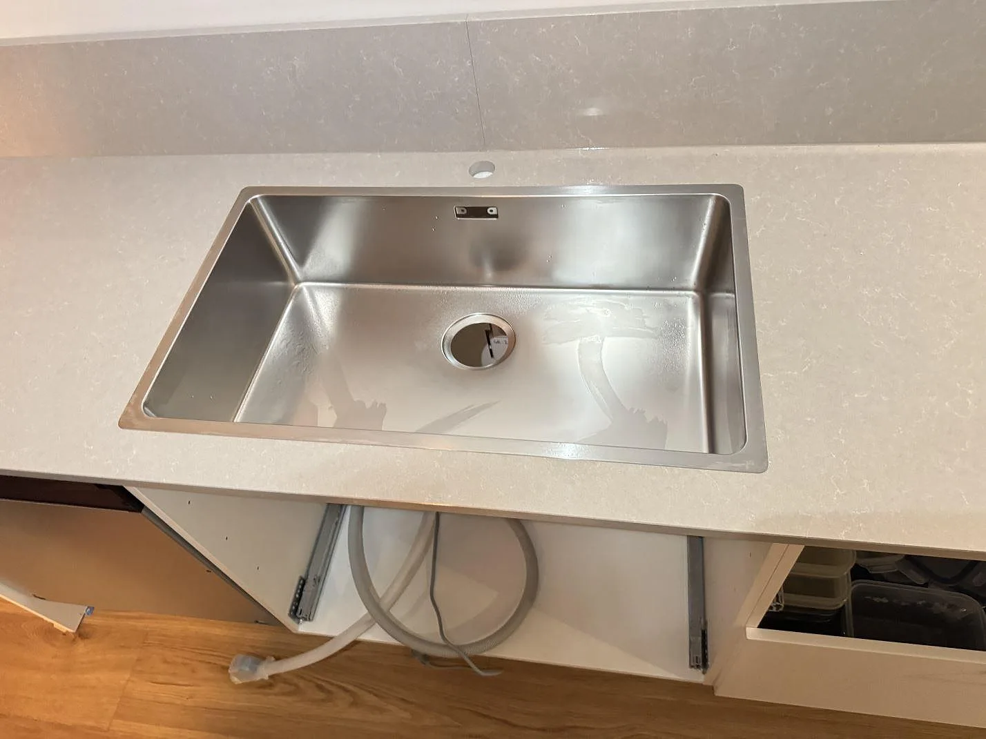 Närbild på rostfri diskho ovanpå en polerad köksbänkskiva i Technistone Noble Ivory White komposit med stänkkant i Jönköping.