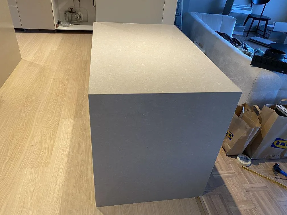 Toppskiva och gavel i polerad Technistone Noble Ivory White komposit på en ljus köksdel under montering i Jönköping.